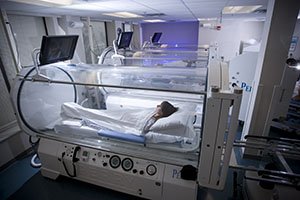 Three Glass Wound Care Chambers with patients laying inside of them