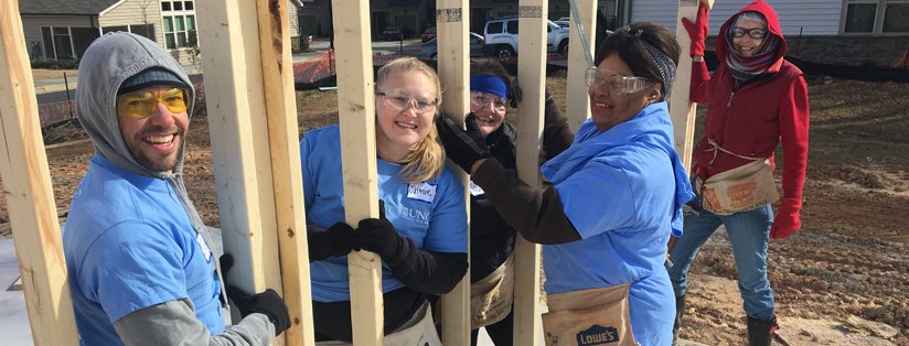 Volunteers work together on building a house frame