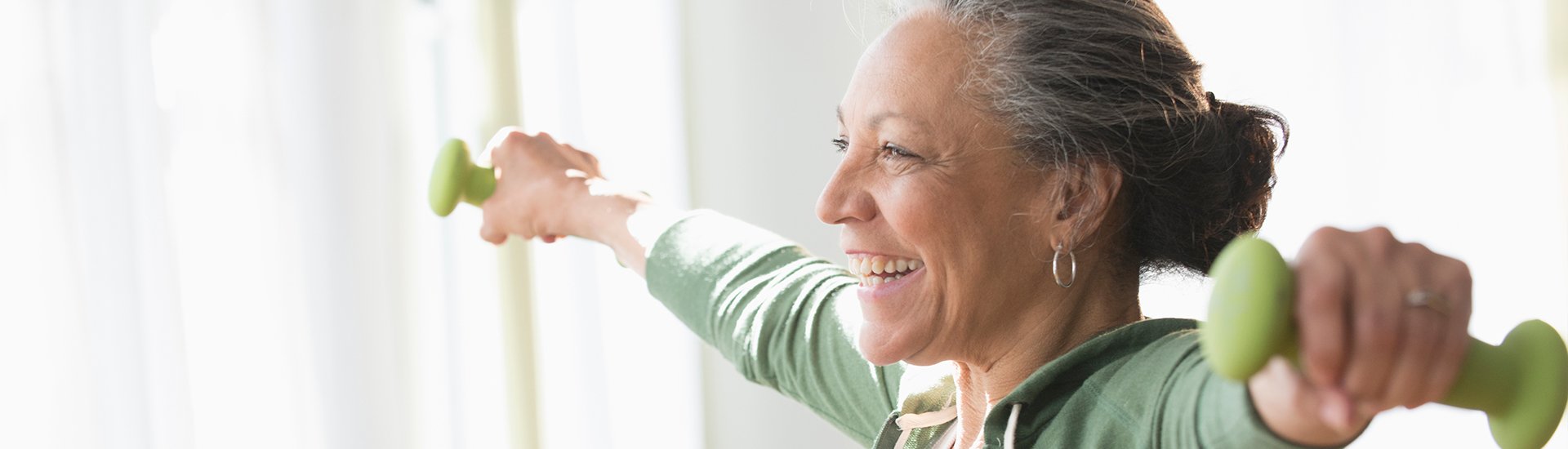 older woman lifting weights, smiling