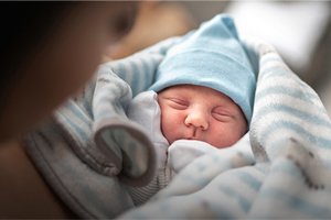 close-up image of newborn baby in blue striped hospital blanket